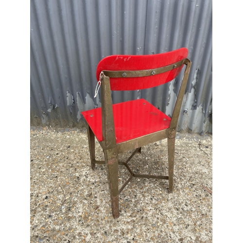 92 - An industrial style metal framed chair with red plastic seat