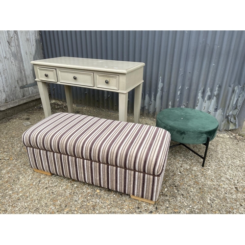 100 - A modern painted three drawer side table together with a green upholstered stool and a fabric ottoma... 