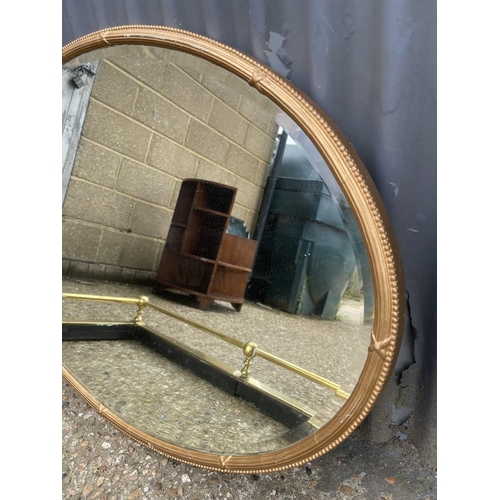 11 - An oval gold gilt framed mirror together with a brass fender