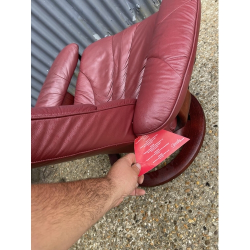 119 - A red leather stressless reclining armchair with stool