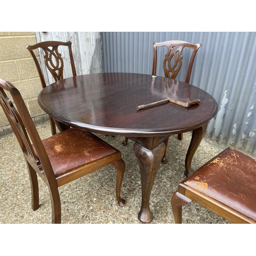 123 - An antique mahogany wind out oval dining table together with four chairs and two extension leaves