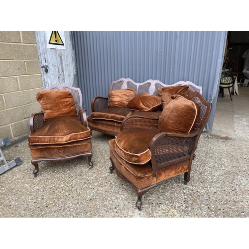 124 - An antique three piece begere lounge suite consisting of two chairs and sofa with cushions.