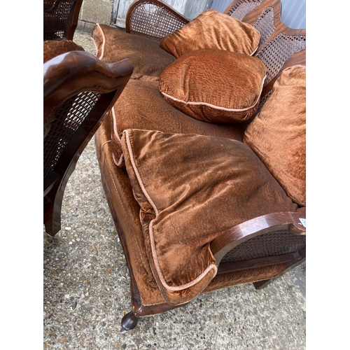 124 - An antique three piece begere lounge suite consisting of two chairs and sofa with cushions.