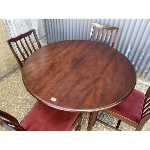 200 - A stag minstrel circular extending dining table with four matching chairs