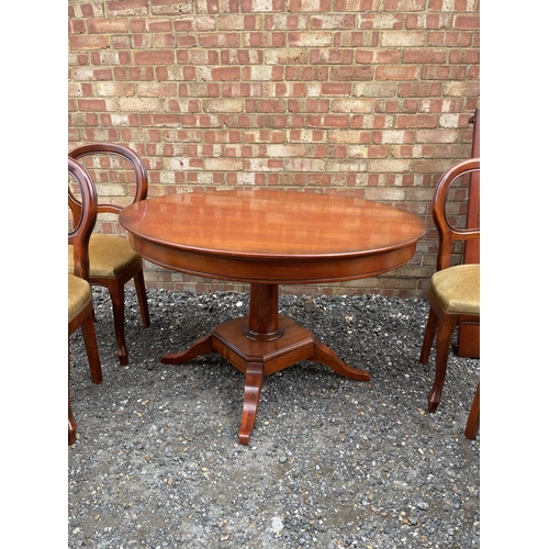 26 - A circular reduction mahogany dining table with extension leaf together with a set of six matching b... 