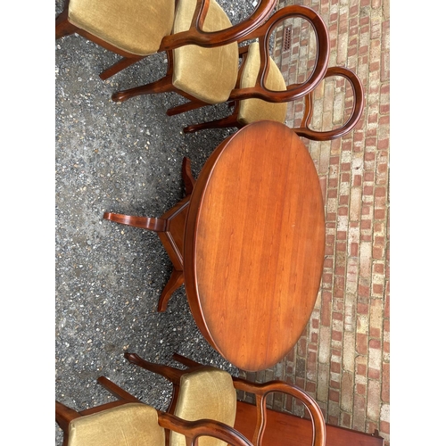 26 - A circular reduction mahogany dining table with extension leaf together with a set of six matching b... 