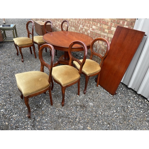 26 - A circular reduction mahogany dining table with extension leaf together with a set of six matching b... 