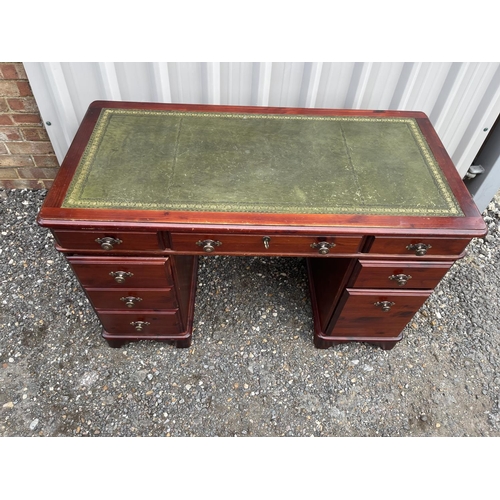 28 - A dark pine kneehole desk with green leather top. Size 120 x 60 cms