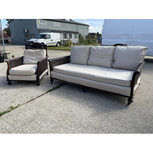 312 - An Edwardian mahogany framed begere sofa with matching armchair, loose cushions upholstered in cream... 