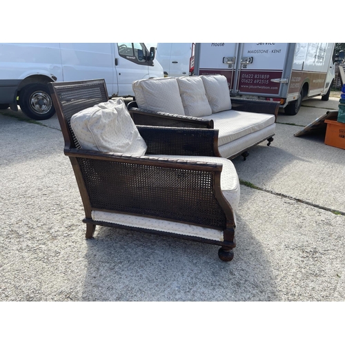 312 - An Edwardian mahogany framed begere sofa with matching armchair, loose cushions upholstered in cream... 