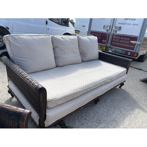 312 - An Edwardian mahogany framed begere sofa with matching armchair, loose cushions upholstered in cream... 