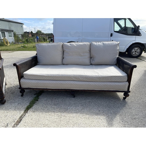 312 - An Edwardian mahogany framed begere sofa with matching armchair, loose cushions upholstered in cream... 