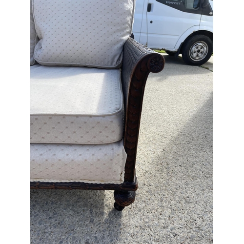 312 - An Edwardian mahogany framed begere sofa with matching armchair, loose cushions upholstered in cream... 