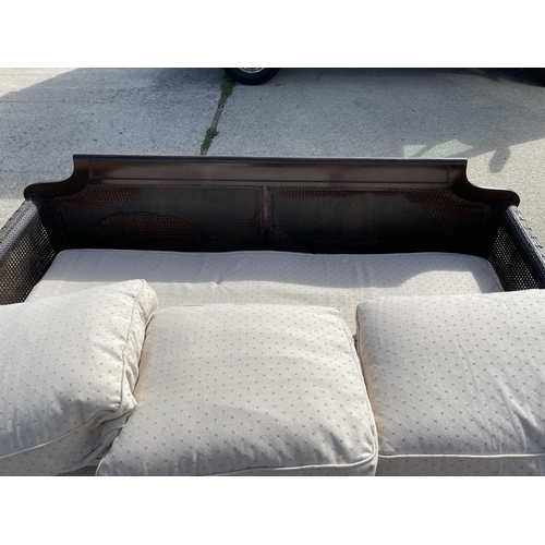 312 - An Edwardian mahogany framed begere sofa with matching armchair, loose cushions upholstered in cream... 