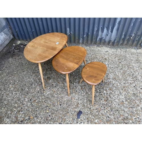 144 - An Ercol light elm pebble nest of three tables