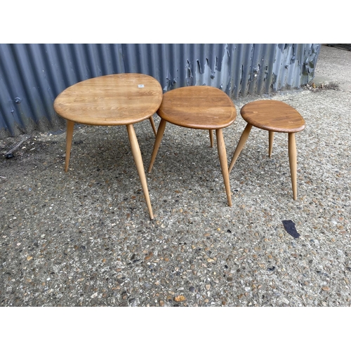 144 - An Ercol light elm pebble nest of three tables