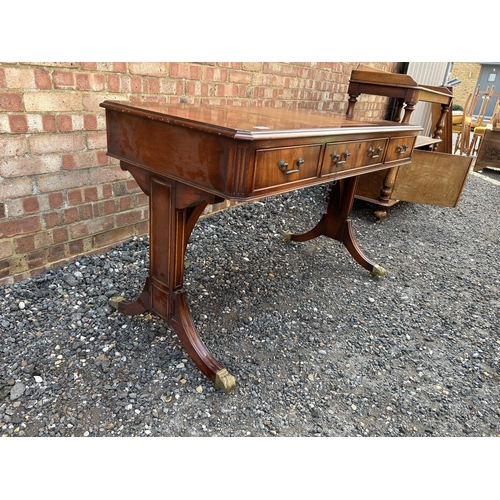 24 - A reproduction mahogany three drawer writing table with brown leather surface