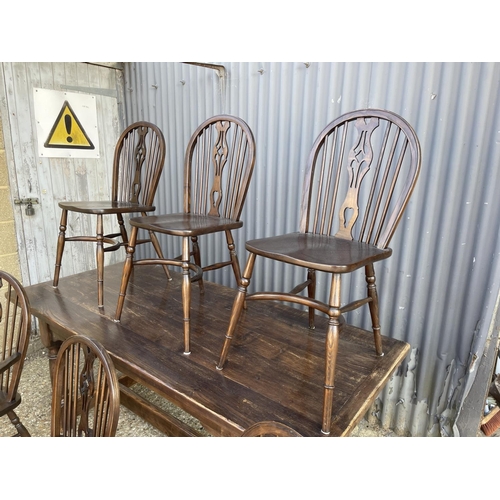 249 - An oak refectory dining table together with six stick back chairs (2 carvers) with crinoline stretch... 