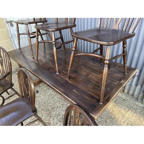 249 - An oak refectory dining table together with six stick back chairs (2 carvers) with crinoline stretch... 