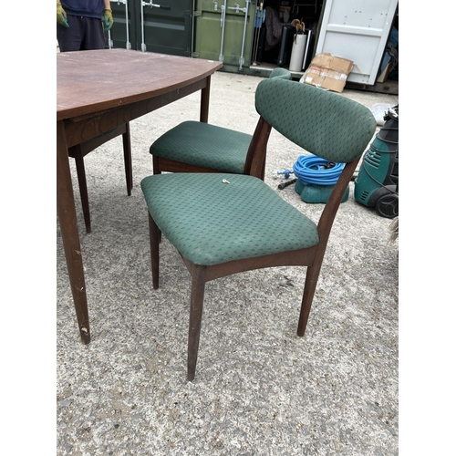 300 - A mid century teak extending dining table together with four matching chairs