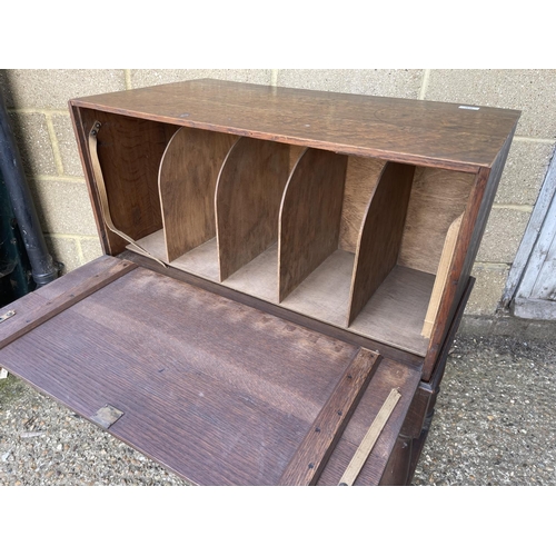 86 - An unusual oak stationery / record cabinet with drop down door on single drawer stand