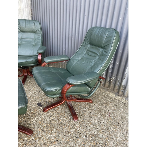 91 - A pair of green leather swivel and recline armchairs with matching footstools