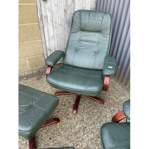 91 - A pair of green leather swivel and recline armchairs with matching footstools