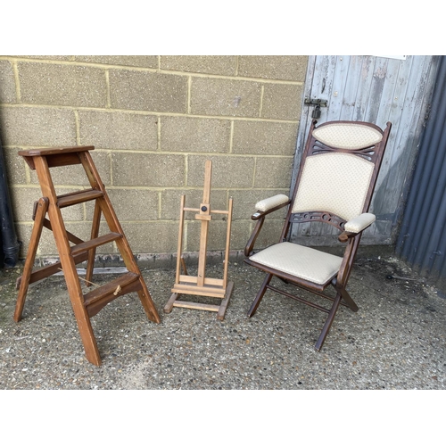 93 - A folding steamer style chair, easel and wooden steps