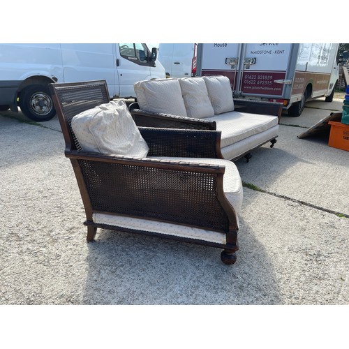 100A - An Edwardian mahogany framed begere sofa with matching armchair, loose cushions upholstered in cream... 