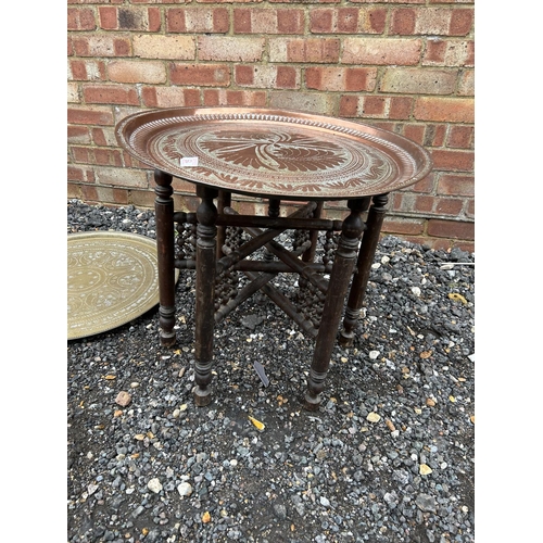 15 - An eastern style copper tray top table with folding hardwood base together with two other trays