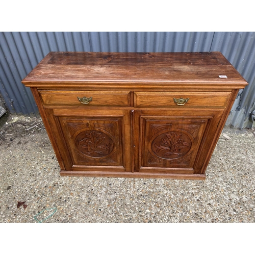 241 - An Edwardian mahogany sideboard with two drawers over two carved panel doors