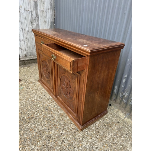 241 - An Edwardian mahogany sideboard with two drawers over two carved panel doors