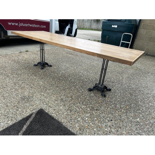 275 - A large light oak refectory table with twin  cast iron supports 240x83