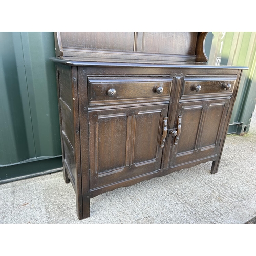 349 - A dark elm Welsh dresser with plate rack top over two drawer and two door base 122cm wide