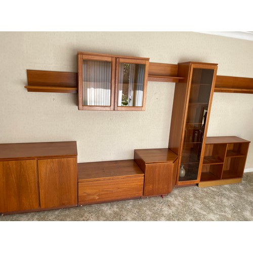 343 - A large multi section teak lounge wall system