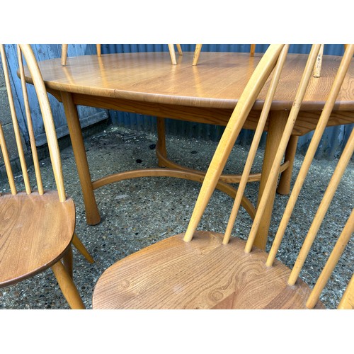 83 - An ercol light elm oval extending dining table together with four stick back chairs (one chair AF)