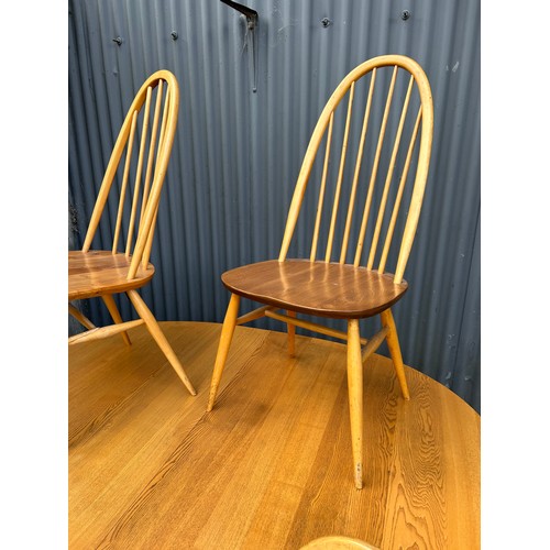 83 - An ercol light elm oval extending dining table together with four stick back chairs (one chair AF)