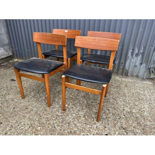 12 - A set of four teak dining chairs with black vinyl seats