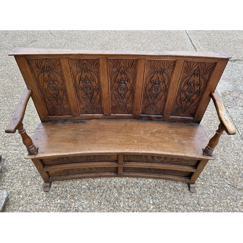 243 - A carved oak ships bench with curved  seat 136cm wide