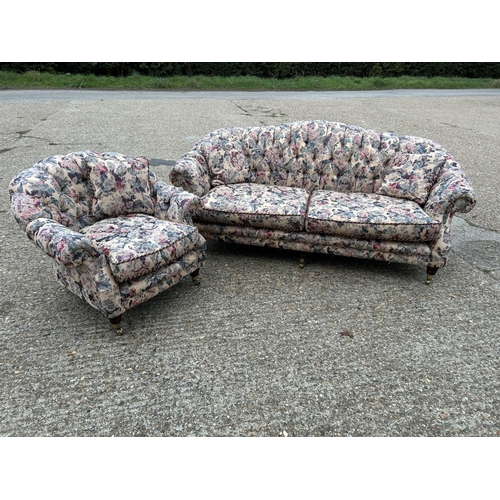 87 - A Victorian style button back sofa and armchair upholstered in a floral pattern