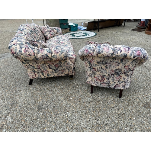 87 - A Victorian style button back sofa and armchair upholstered in a floral pattern