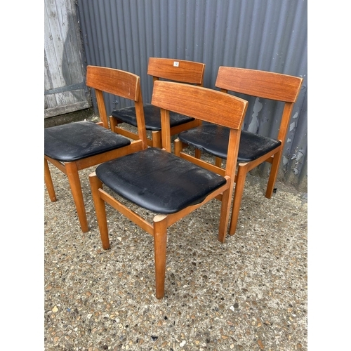 12 - A set of four teak dining chairs with black vinyl seats