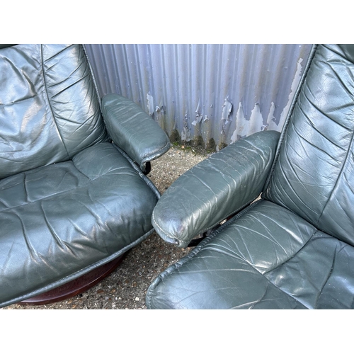 164 - A pair of green leather Ekornes stressless reclining chairs with footstools