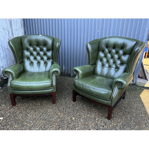 350a - A pair of green leather chesterfield wing back armchairs