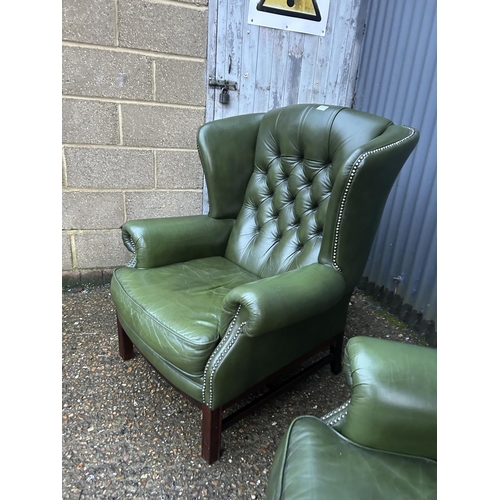 350a - A pair of green leather chesterfield wing back armchairs