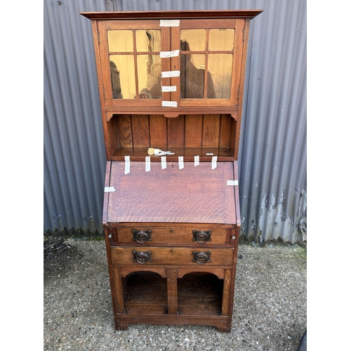 4 - An arts and crafts oak bureau bookcase with glazed top over shelves and two drawers