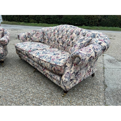 107 - A Victorian style button back sofa and armchair upholstered in a floral pattern