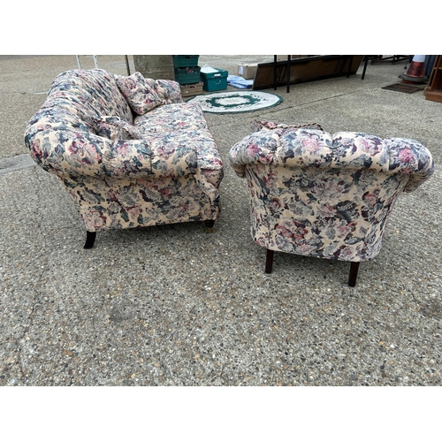 107 - A Victorian style button back sofa and armchair upholstered in a floral pattern