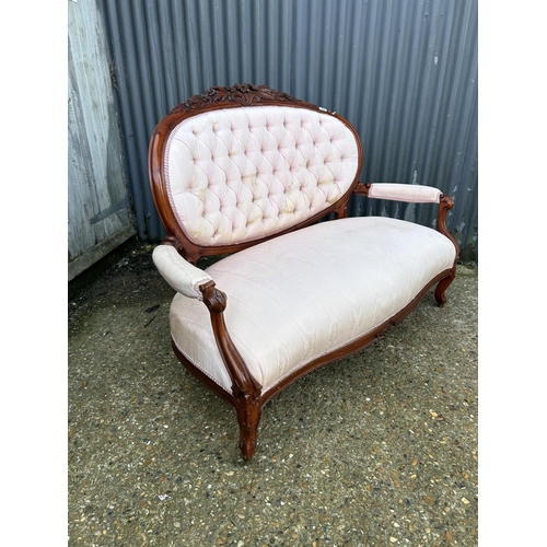 126 - An ornate mahogany framed button back love seat upholstered in pink
