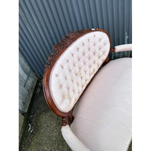 126 - An ornate mahogany framed button back love seat upholstered in pink